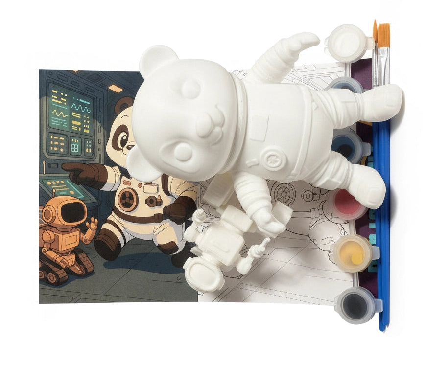 White astronaut toy with paint supplies and a coloring book on a white background